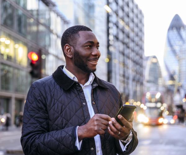 Businessman looking away from camera checking smart phone.