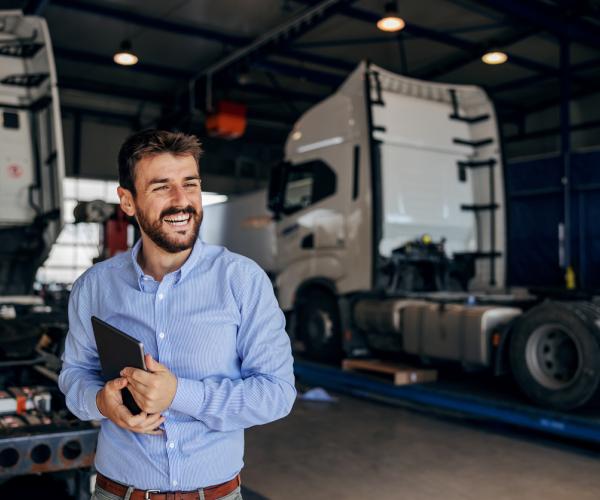 Worker with tablet with trucks in the background